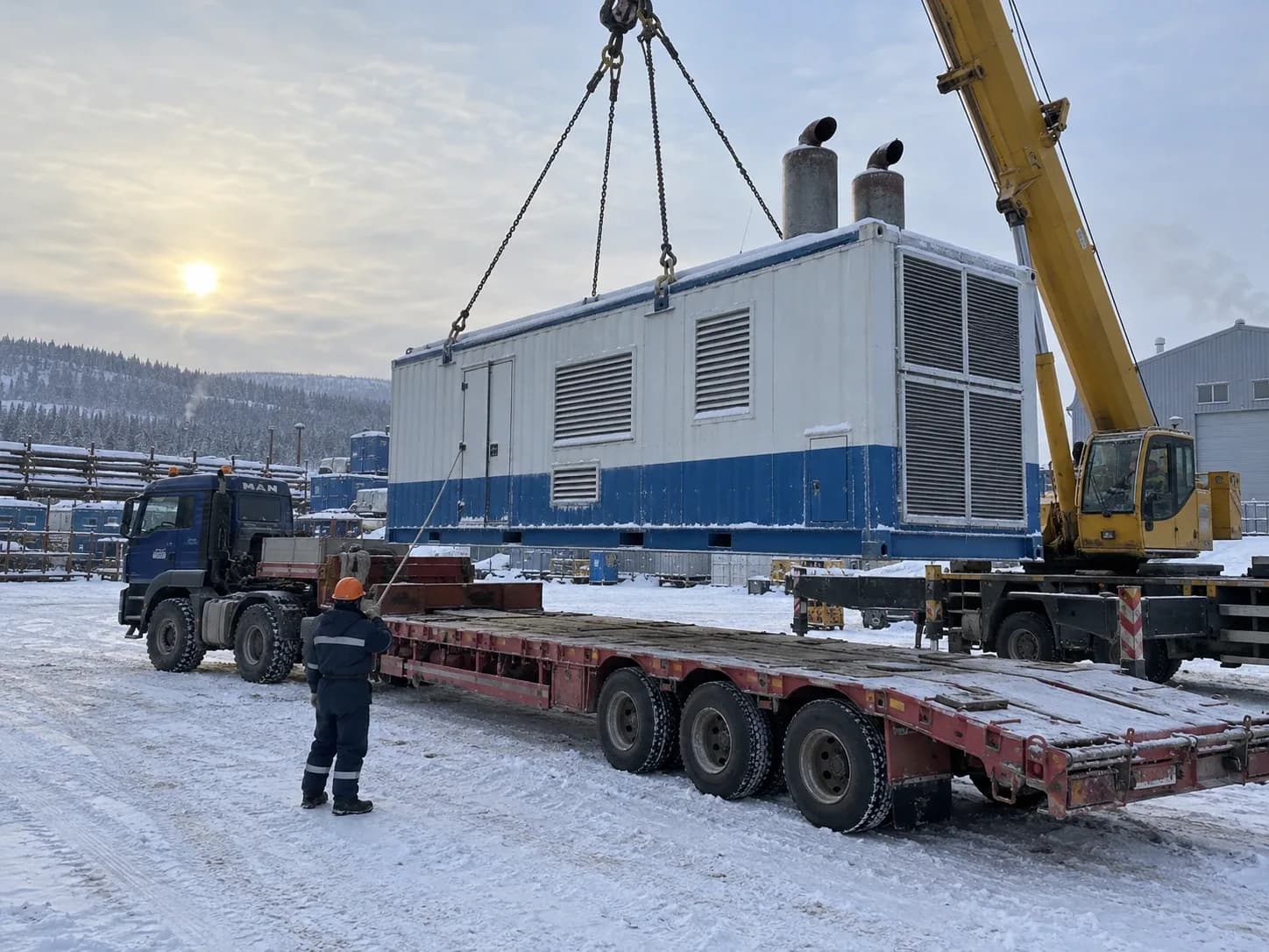 Кран грузит блок-контейнер энергоблока на трал зимой
