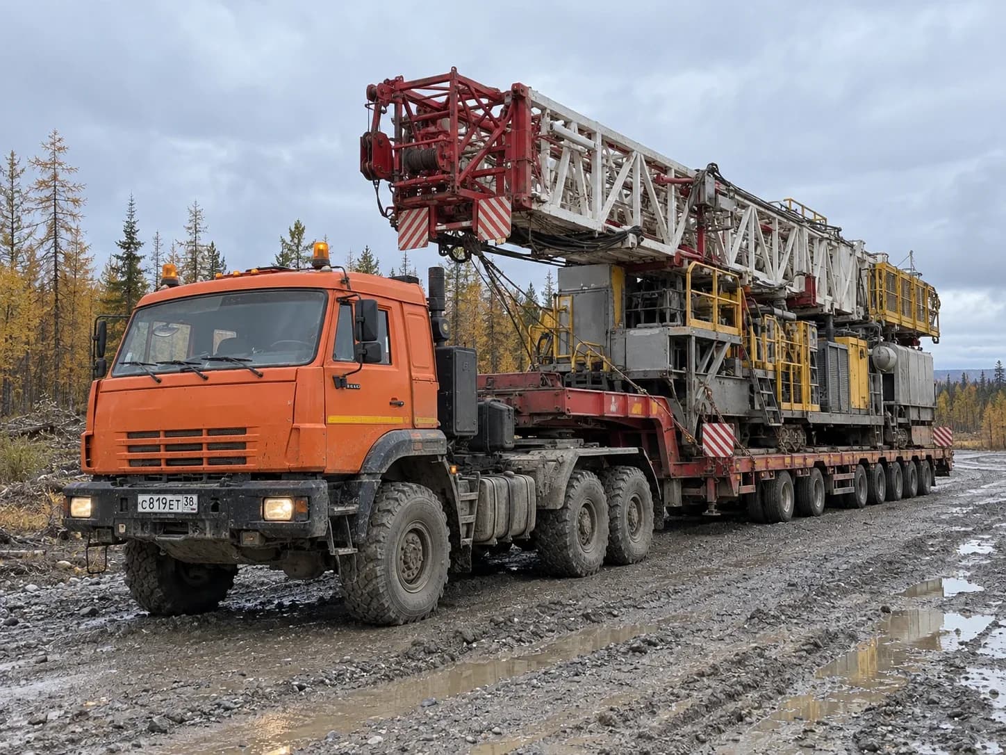 Буровая установка со сложенной мачтой целиком на трале за тягачом 6×6